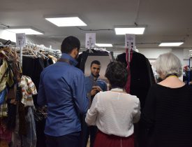 Deux femmes solidaires habillent un homme d'un costume professionnel.